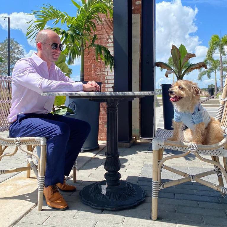 Geoffrey Fahey and google the dog oak and ola tampa restaurant table outside brickwall in-rear and blue sky and clouds